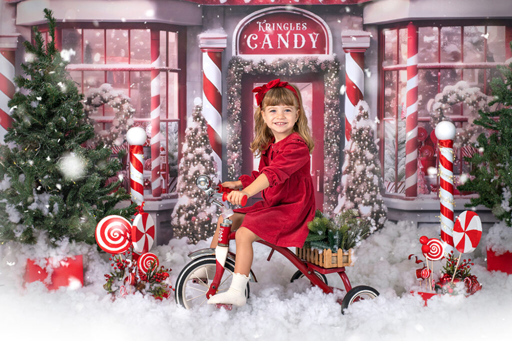 fotografia escolar de navidad con escecnario navideño y niña en triciclo