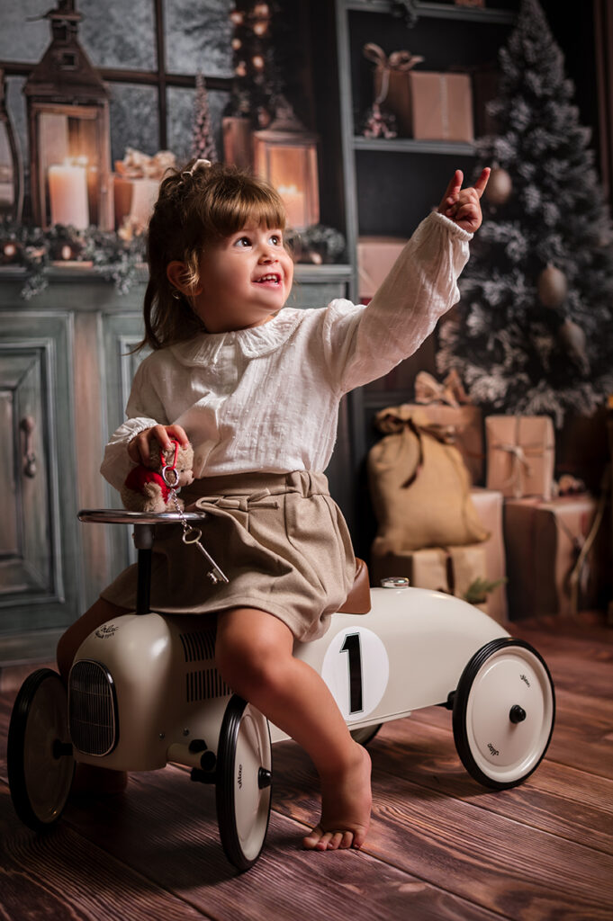 retrato infantil niña en triciclo en escenario de navidad